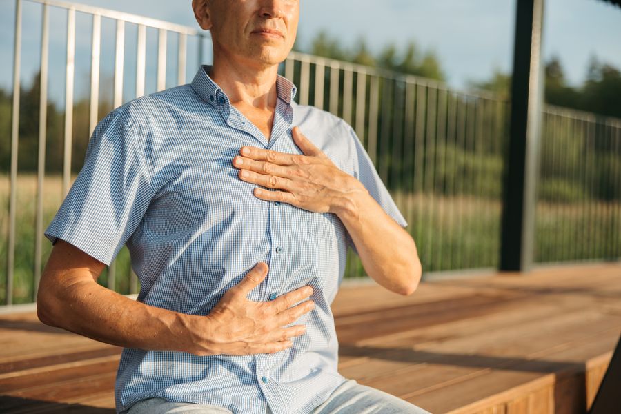 Uomo con una mano sul petto e una sull'addome che respira con calma